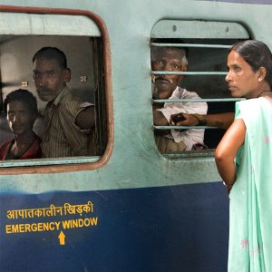 Gare de Delhi, trois hommes dans un wagon fixent le photographe tandis qu'une femme sur le quai scrute l'horizon, en 2011. Série Regard tissé.