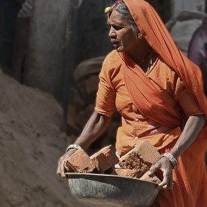 A Jodhpur, femme en sari orange transportant dans une bassine des briques pour la construction d'un immeuble, en 2011. Série Regard incandescent.
